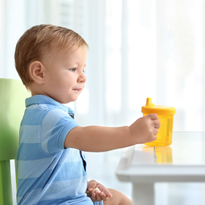 How sippy cups and bottles affect a toddlers teeth 3 Toddler holding a yellow sippy cup, representing how sippy cups and bottles affect a toddlers teeth